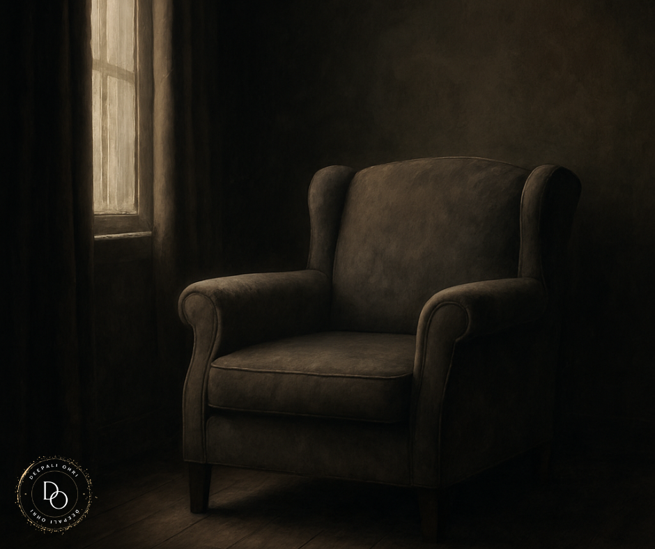 An empty, worn armchair bathed in soft, warm daylight streaming through a partially draped window in a dimly lit room.