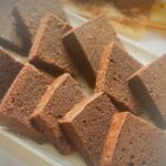 Freshly sliced moist chocolate butter cake arranged neatly on a white tray, showing the soft and fluffy texture of the cake.