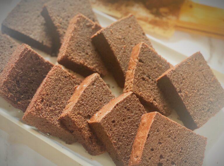 Easy Chocolate Butter Cake Recipe (Super Moist & Fluffy!) Freshly sliced moist chocolate butter cake arranged neatly on a white tray, showing the soft and fluffy texture of the cake.