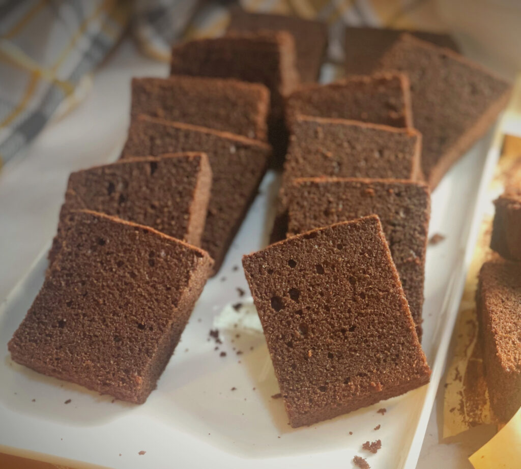 Neatly arranged chocolate butter cake slices on a white tray, showing a moist and dense crumb with a rich chocolatey texture.