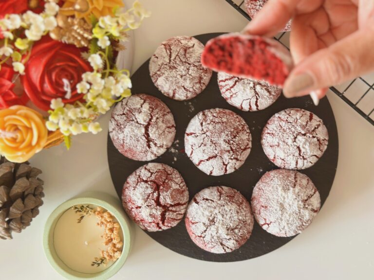 Red Velvet Crinkle Cookies – Bakemas 2025, Episode 1 | Soft, Fudgy, Snowy Holiday Cookies Red velvet crinkle cookies dusted with powdered sugar on a black plate, with one cookie broken open to show the soft fudgy center.