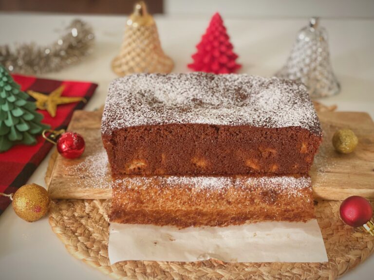 Gingerbread Pear Loaf Cake Gingerbread pear loaf cake dusted with powdered sugar, sliced and served on a wooden board with festive Christmas decorations