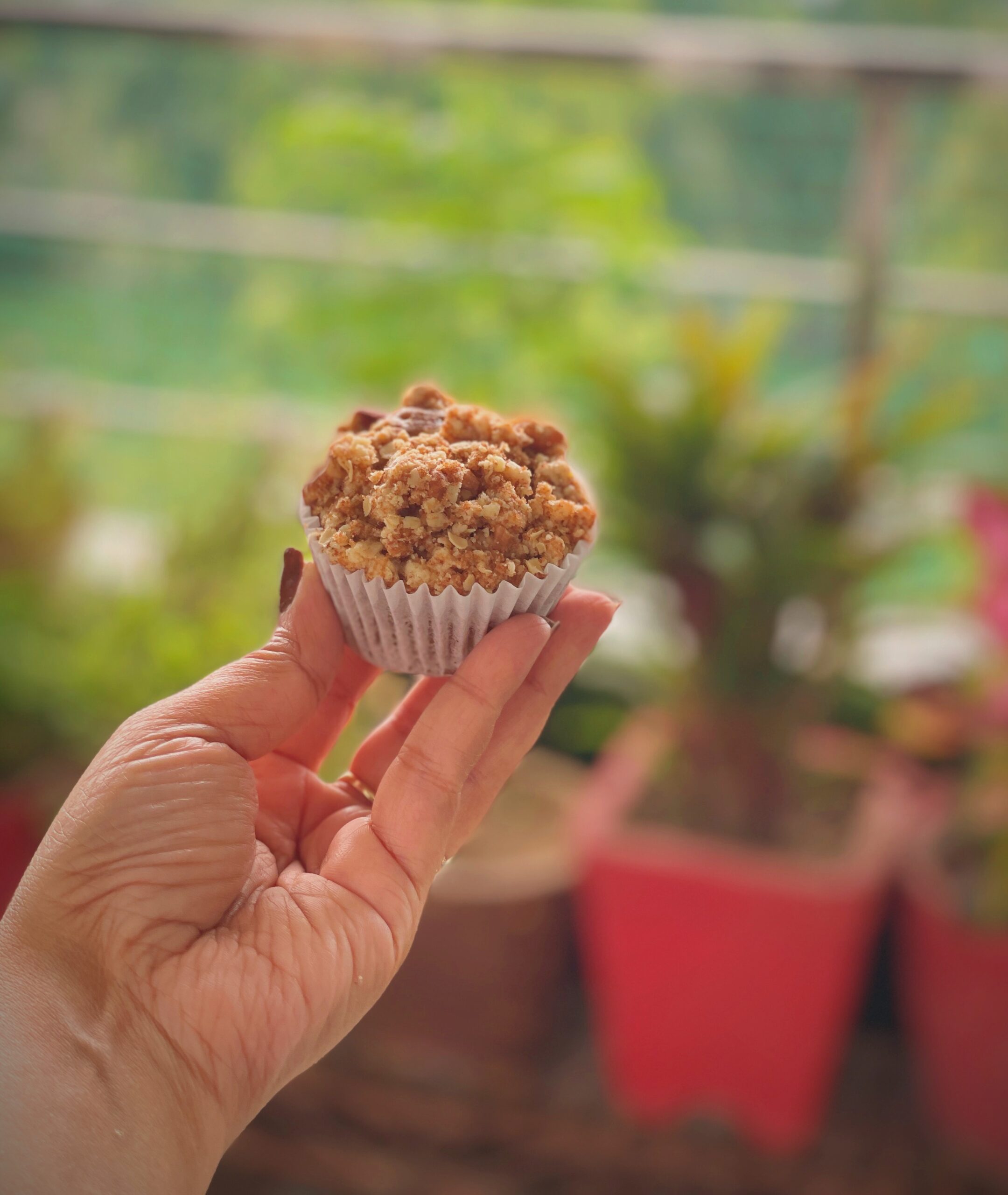 Hand holding eggless apple crumble muffin with crunchy streusel topping