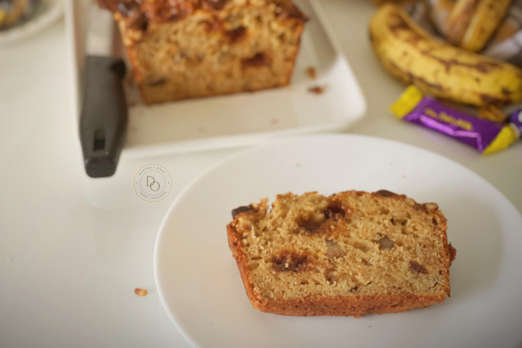 Slice of banana streusel bread showing soft crumb with caramel and walnut pieces