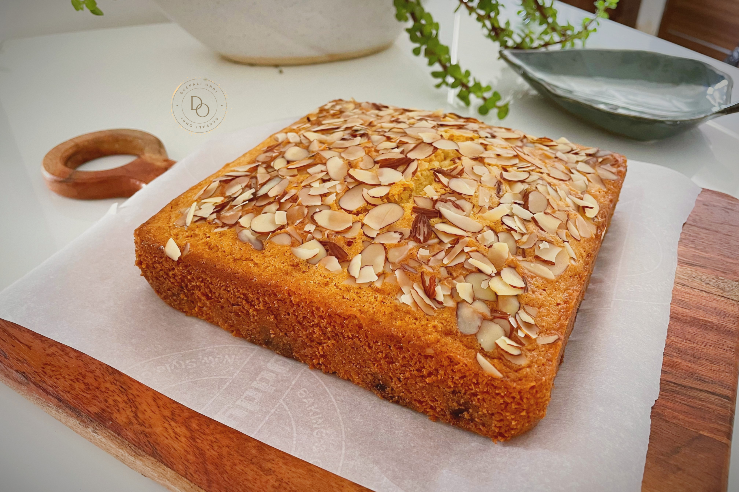 Eggless blueberry almond tea cake topped with sliced almonds placed on parchment paper over a wooden platter