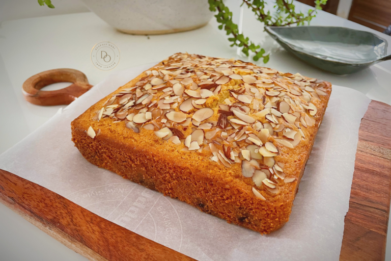 Eggless blueberry almond cake topped with sliced almonds baked in a square pan
