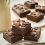 Stack of eggless Oreo brownies topped with crushed Oreo cookies on a serving plate