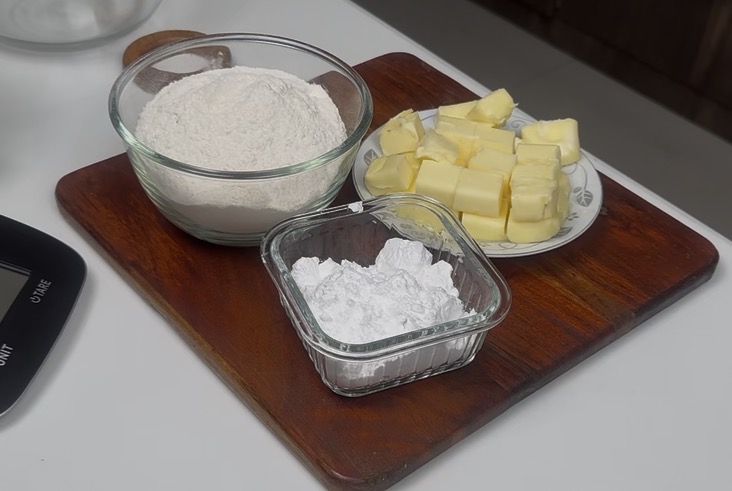 Three ingredients for butter cookies: soft butter, powdered sugar, and flour arranged in bowls