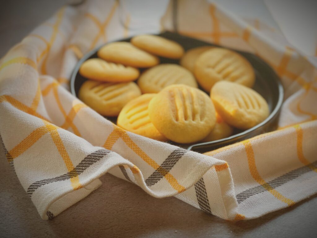 Eggless condensed milk cookies in a cast iron pan wrapped in a yellow checkered tea towel