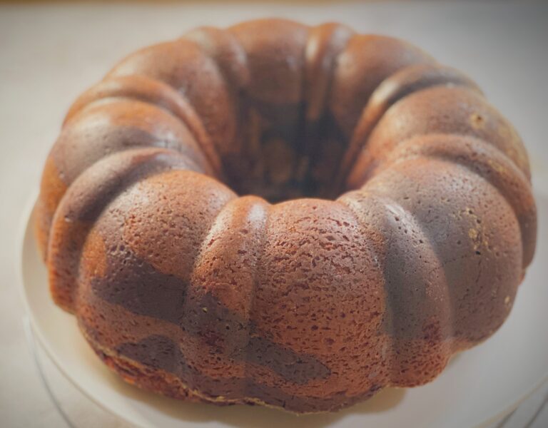 Whole red velvet marble cake dusted with powdered sugar in a bundt shape