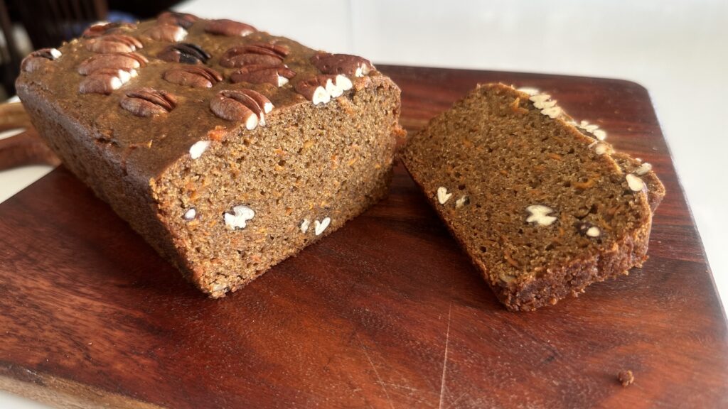 Eggless Date & Carrot Cake sliced on a wooden board showing the moist crumb