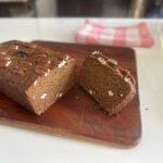 Eggless Date & Carrot Cake whole loaf with slice on a wooden board