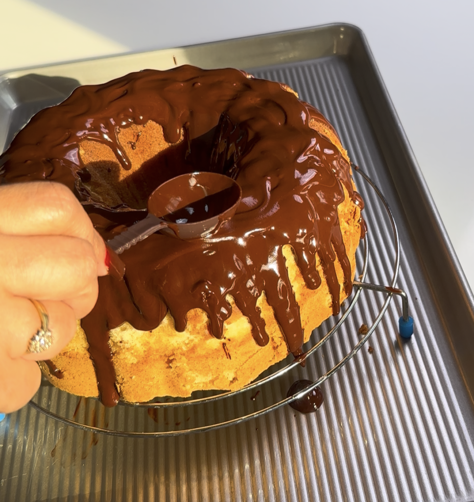 Pouring glossy chocolate glaze over a vanilla bundt cake