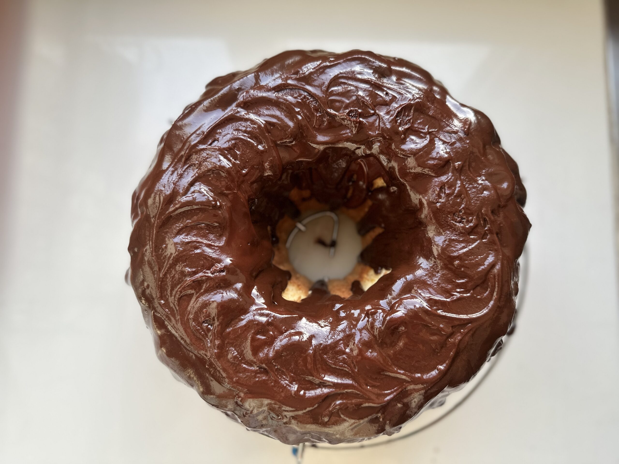 Top-down view of a whole vanilla bundt cake covered in glossy chocolate glaze