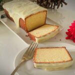 Condensed milk pound cake with lime glaze, sliced and served with a fork on a white plate