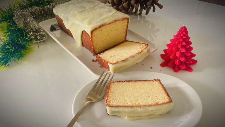 Condensed milk pound cake with lime glaze, sliced and served with a fork on a white plate