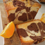 Sliced chocolate orange marble cake on a wooden board with orange wedges