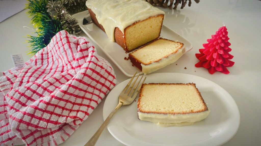 Sliced condensed milk pound cake with lime glaze styled with a red checked tea towel