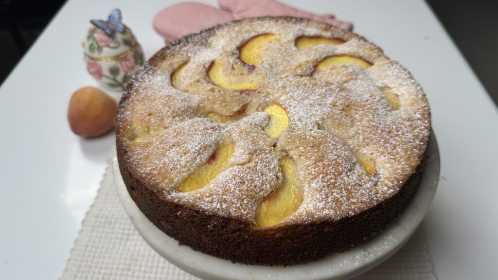 Close-up angled view of peach butter cake showing soft peach slices baked into the top