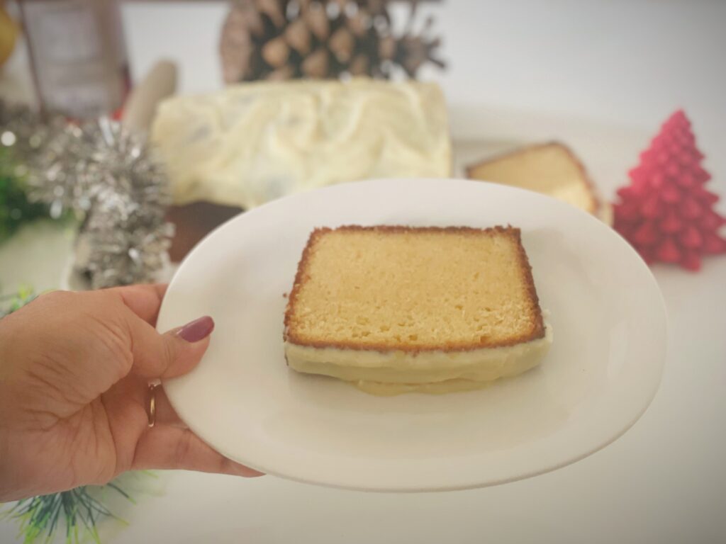 Slice of condensed milk pound cake with lime glaze held on a white plate