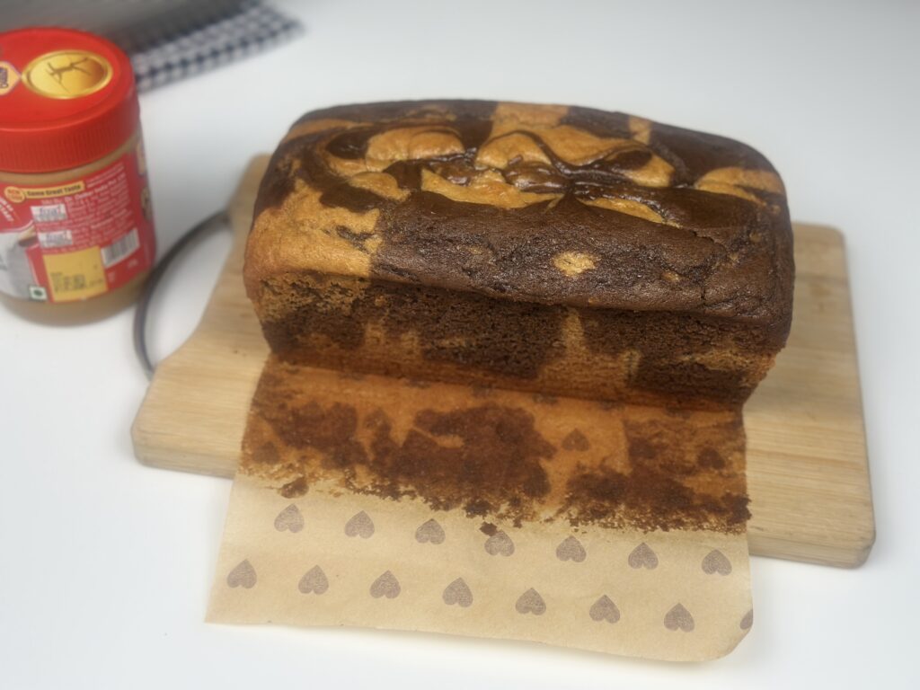 Top view of whole eggless peanut butter marble loaf cake with peanut butter jar