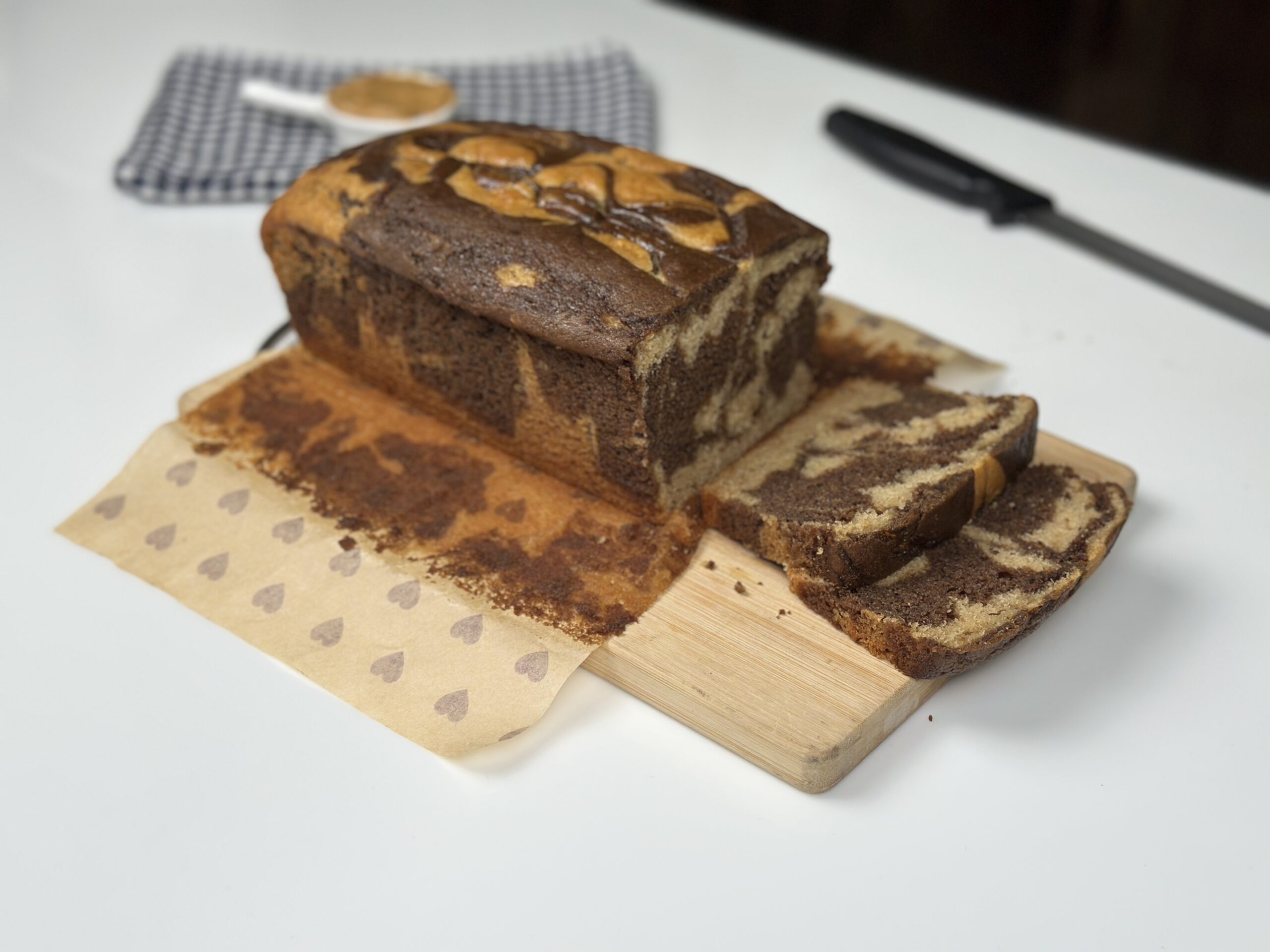 Eggless marble peanut butter loaf cake with cut slices on a wooden board