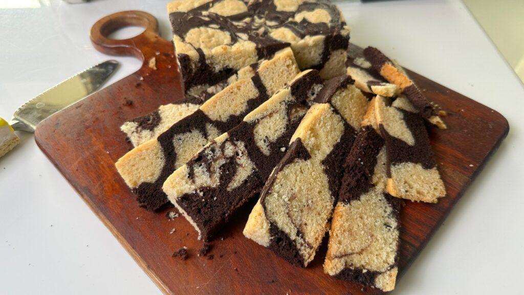 Eggless marble cake cut into bars and fanned out on a wooden board
