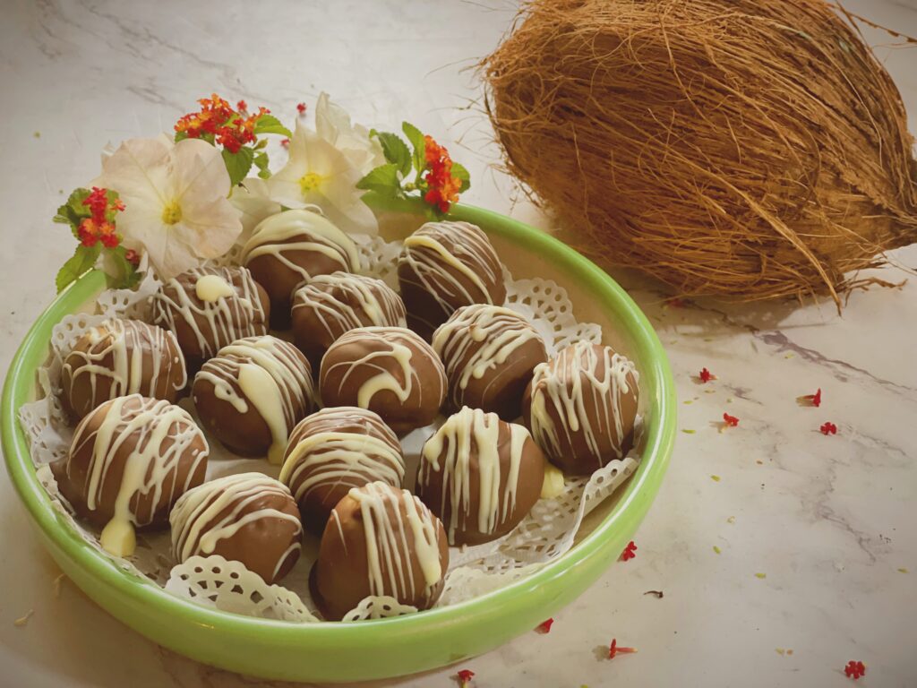 Bowl of chocolate coconut balls with a fresh coconut and flowers