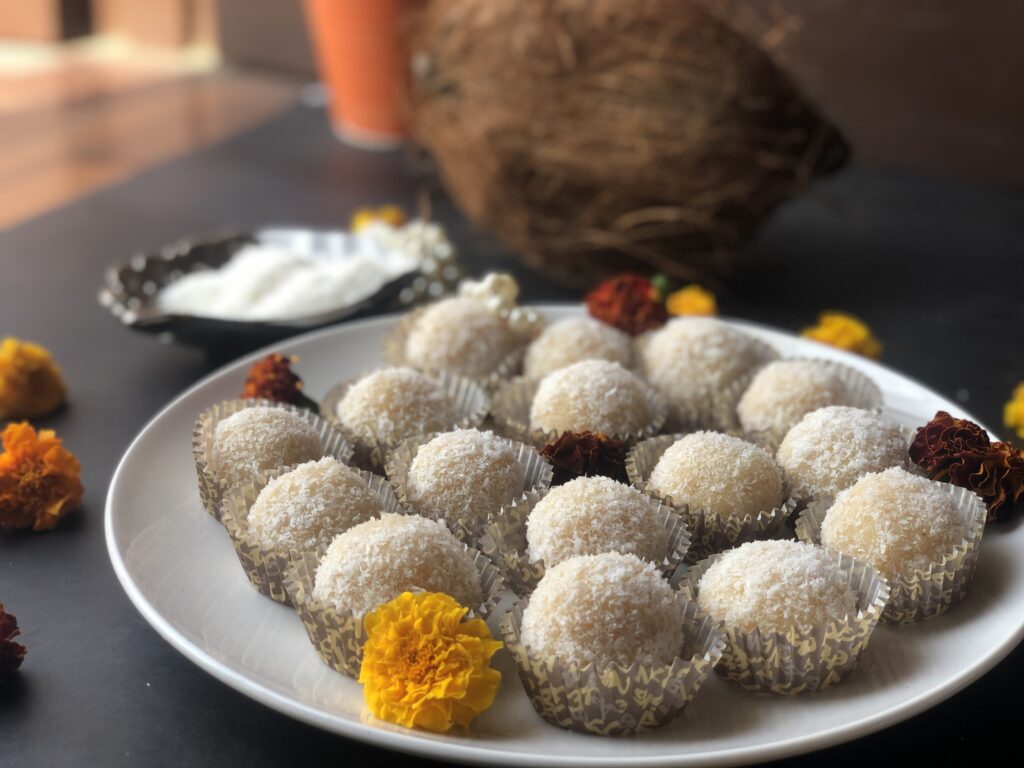 Rows of coconut ladoos in paper liners decorated with a marigold