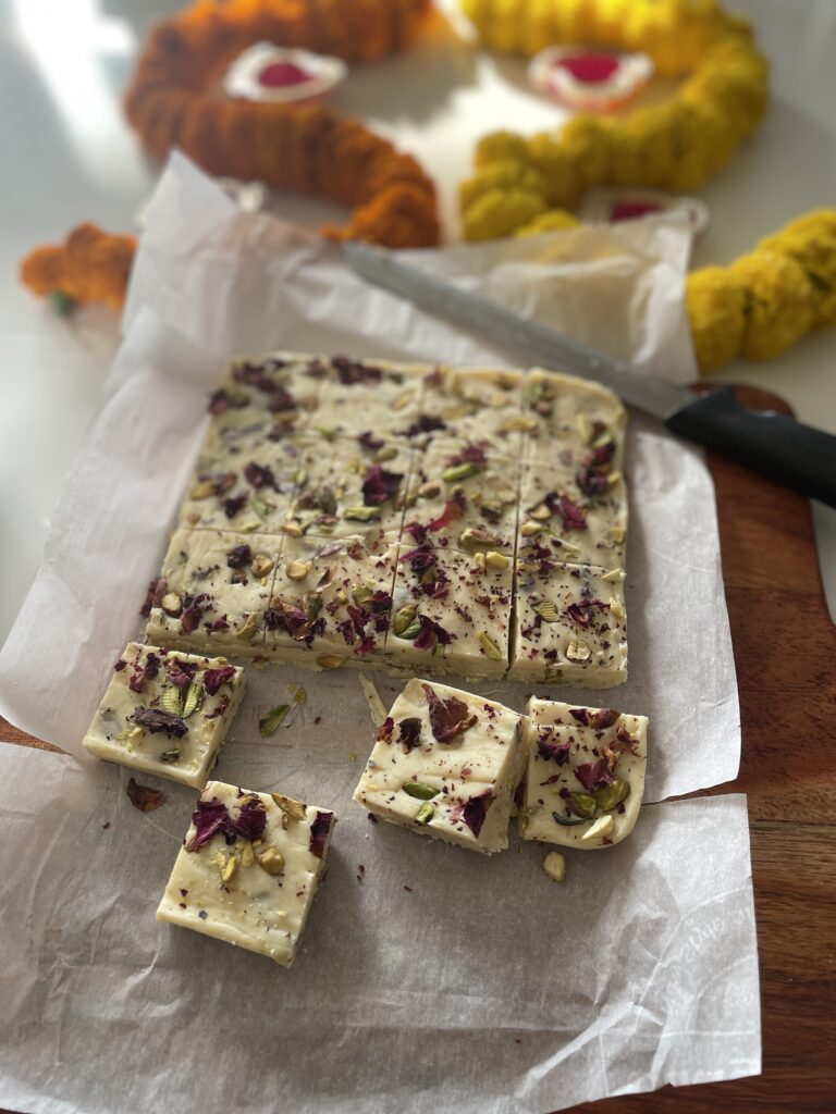 Rasmalai white chocolate fudge being cut into squares with a knife