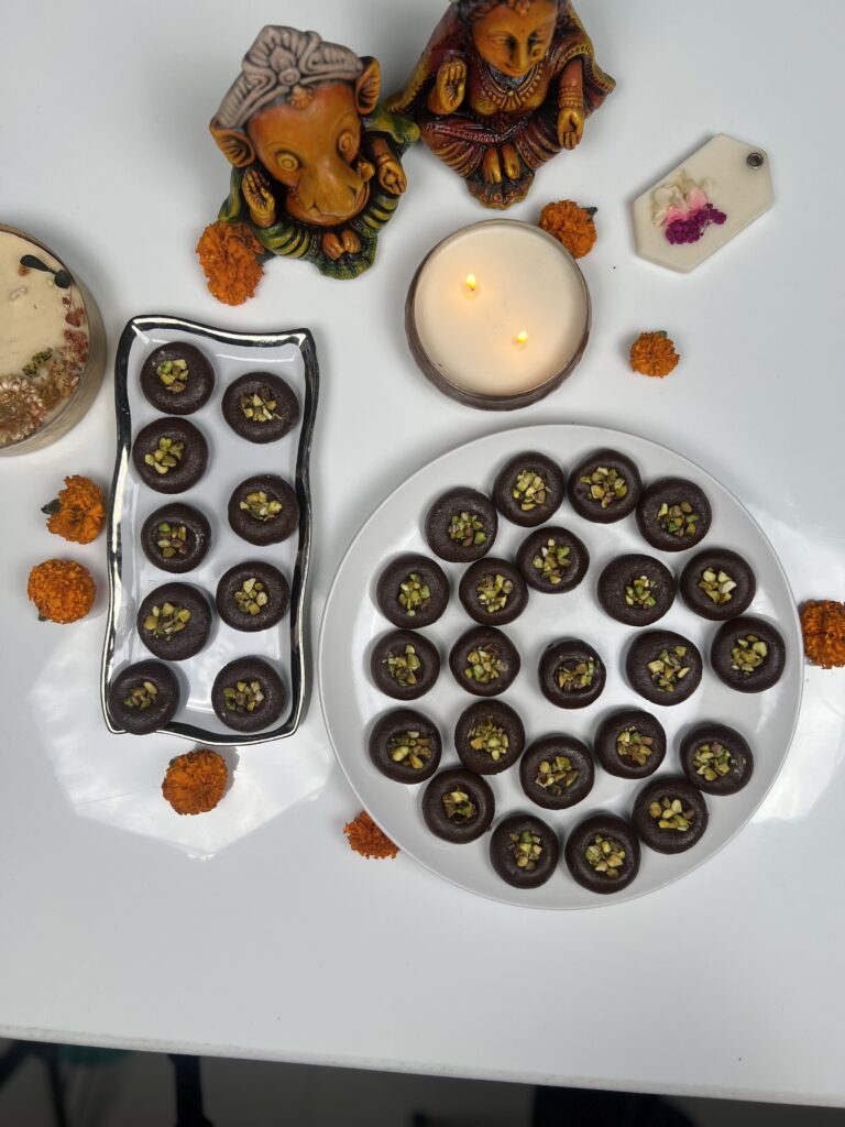 Chocolate pedas on a plate and a gift tray with marigolds, ready for Diwali gifting