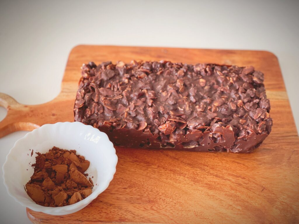 Set no-bake chocolate biscuit cake with almonds on top, before dusting with cocoa