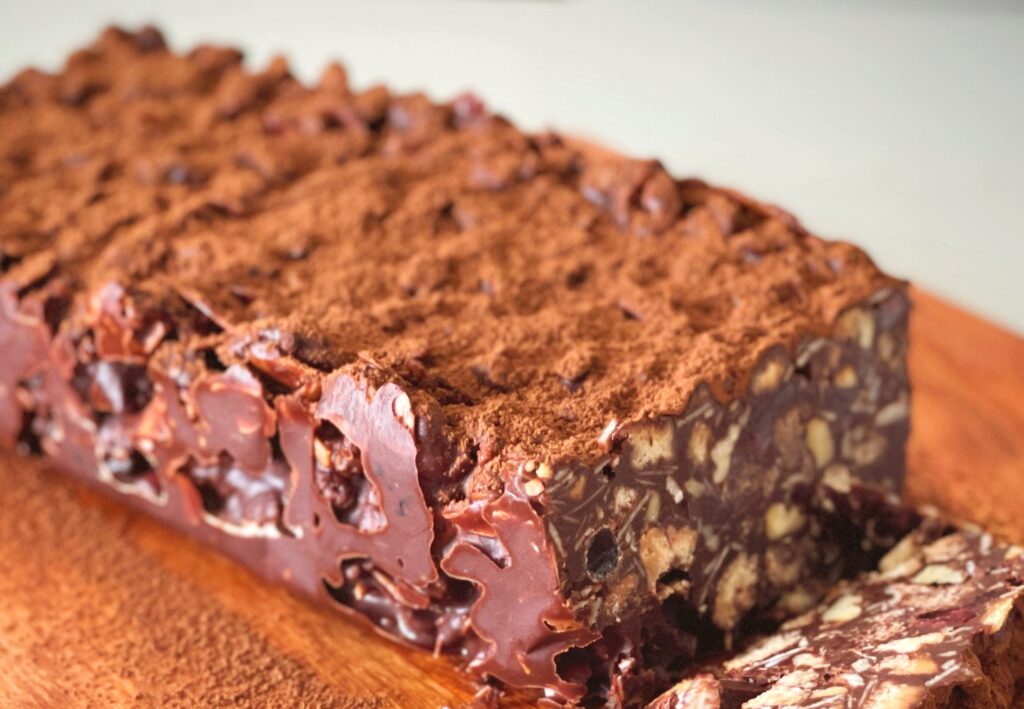 Close-up of fudgy no-bake chocolate biscuit cake with almonds and biscuit pieces