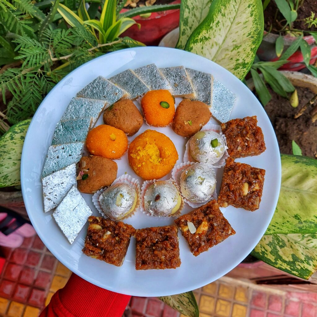 Plate of assorted homemade Diwali sweets including kaju katli, ladoos and barfi