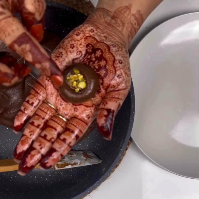 Shaping a chocolate peda by hand with a thumbprint filled with pistachios