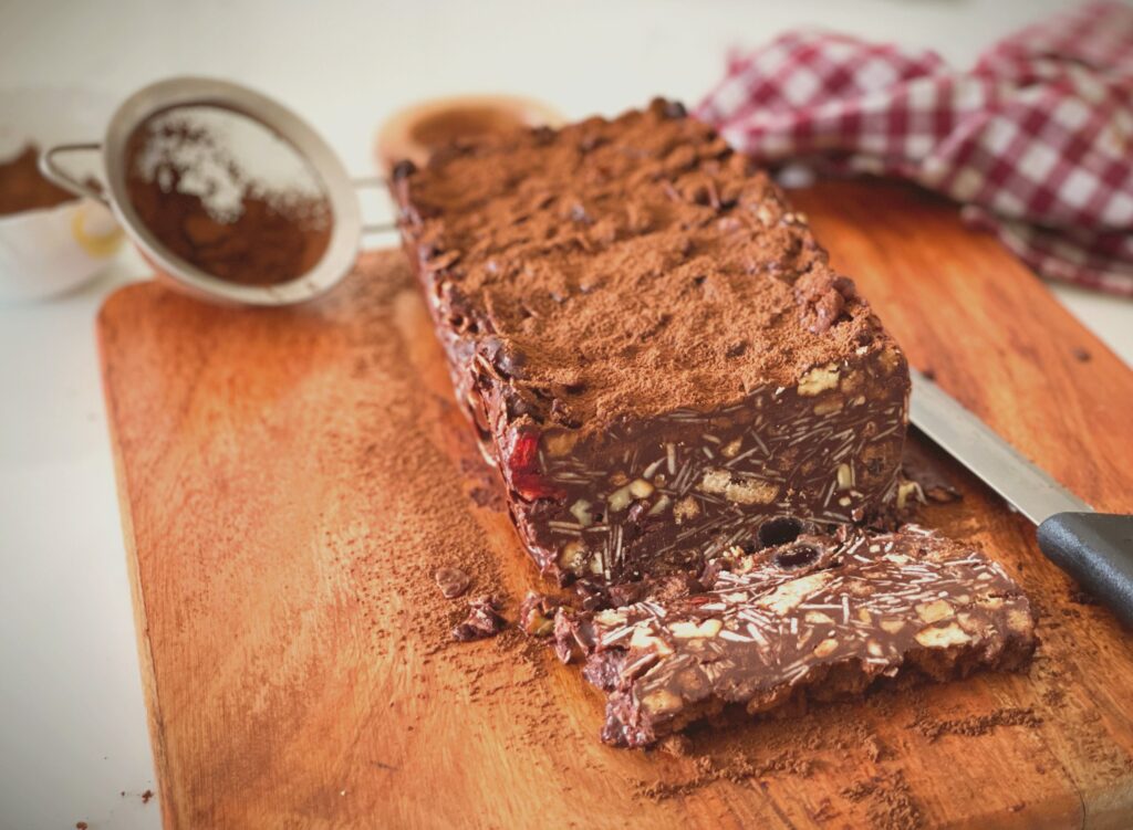 Slice of no-bake chocolate biscuit cake showing nuts and biscuits inside
